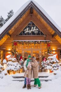 a family posing in front of a christmas store at Tsarstvo Korolevstvo in Roshchino