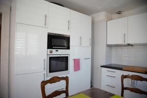 cocina con armarios blancos, mesa y sillas en Laincel - Clim - Balcon, en Arles