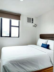 a large white bed in a room with a window at airobedz MAKATI - A Value Hotel in Manila