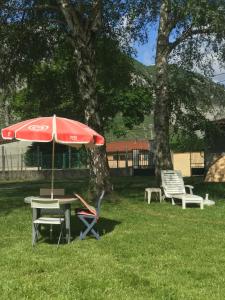 una mesa de picnic con sombrilla y 2 sillas en appartement à Tarascon sur Ariège le Sabart en Tarascon-sur-Ariège