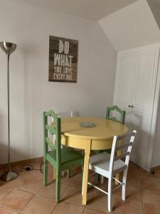 a yellow table with chairs and a sign on the wall at Cottage en duplex meublé au calme proche Orleans in Ardon