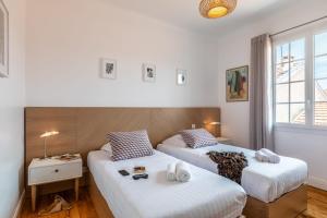 - 2 lits dans une chambre aux murs blancs dans l'établissement Superbe appartement plein de charme à 5min de la plage, à Biarritz
