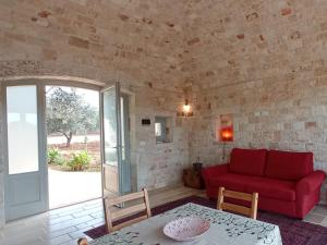 a living room with a red couch and a table at Masseria - Trulli Genius Loci Dimore in Monopoli