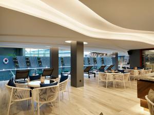 a dining room with tables and chairs and windows at The Oceanic Sportel Phuket - SHA Extra Plus in Phuket