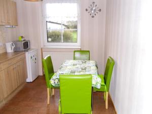 una cocina con una mesa con sillas verdes y una ventana en Ferienwohnung Gluehwuermchen, en Barnin