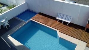 a swimming pool with a bench next to a building at Colônia de Férias SITRAEMFA in Peruíbe