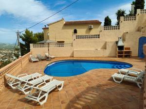 a swimming pool with lounge chairs and a house at Villa Maryvilla 0210 in Calpe