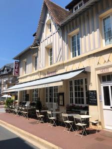 a row of tables and chairs outside of a building at Hotel Le Normand in Houlgate
