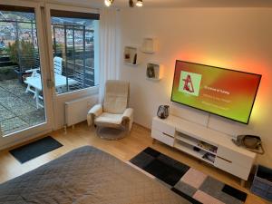 een woonkamer met een flatscreen-tv en een stoel bij Appartement mit herrlicher Aussicht übers Murgtal in Baiersbronn