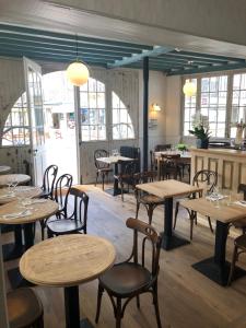 un restaurant avec des tables et des chaises en bois ainsi que des fenêtres dans l'établissement Hotel Le Normand, à Houlgate