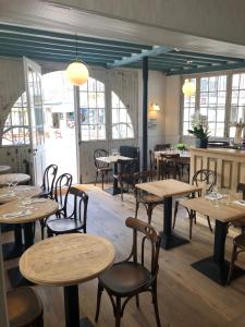 a restaurant with wooden tables and chairs and windows at Hotel Le Normand in Houlgate