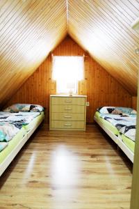 a attic room with two beds and a dresser and a window at Penzion Maruška in Dolní Moravice