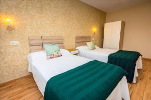 two beds in a hotel room with green sheets at Apartamentos Navalin in Tapia de Casariego +150 photos