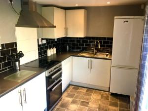 a kitchen with white cabinets and a sink and a refrigerator at Remarkable 2-Bed Apartment in Norfolk Broads in Norwich