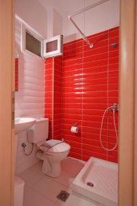 a red bathroom with a toilet and a sink at Mavridis Rooms 2 in Nikiti