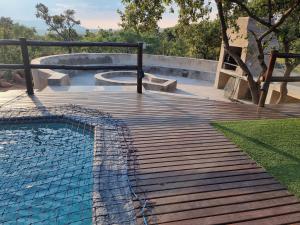 una rampa de madera que conduce a una piscina con piscina en Livingstone Bush Lodge, Mabalingwe, en Bela-Bela