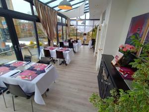 un restaurante con mesas y sillas blancas y ventanas en Dukes Folly Hotel en Southport