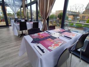 a dining room with white tables and chairs and windows at Dukes Folly Hotel in Southport