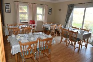 a dining room with tables and chairs and windows at Slieve League House B&B in Teelin