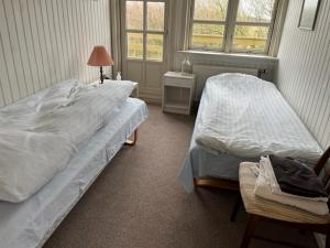 1 dormitorio con 2 camas, silla y ventana en Munkebo B&B, Thy, en Thisted
