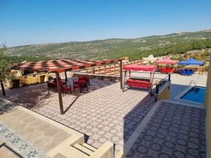 een patio met een tafel en stoelen naast een zwembad bij Green forest farm in Ajloun