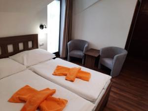 um quarto com 2 camas e 2 toalhas cor-de-laranja em Hotel Flora em Bešeňová