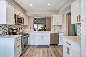 a kitchen with white cabinets and wooden floors at Chic Palm Desert Condo with Resort-Style Amenities! in Palm Desert