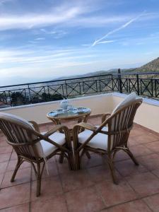 patio z 2 krzesłami i stołem na balkonie w obiekcie Gerania Villa w mieście Písia