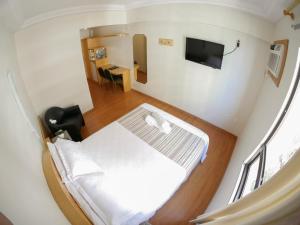 a white bed in a room with a tv at Icaraí Praia Hotel in Niterói