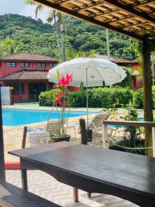 a picnic table with an umbrella next to a pool at Chales Terra Pura in Camburi