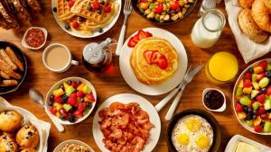 einen Holztisch mit Frühstücksteller in der Unterkunft Hotel Meriton in Mumbai