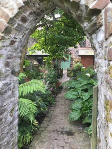 un arco de piedra en un jardín con plantas en The Hermitage en Great Torrington