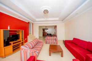 a living room with a red couch and a tv at Fleur Guest House in Kigali