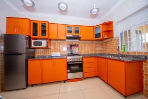 a kitchen with orange cabinets and stainless steel appliances at Fleur Guest House in Kigali