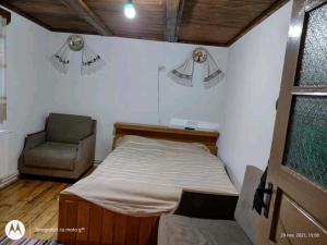 um pequeno quarto com uma cama e uma cadeira em Casa Sașilor em Arieşeni