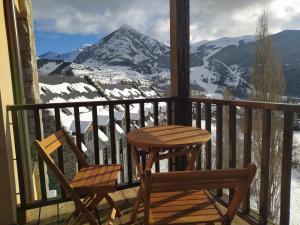 una mesa y una silla en un balcón con una montaña nevada en Apartamentos Ball Benas Edificio Prados de Velarta en Cerler