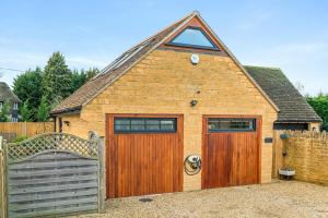 a large brick building with a gate and a garage at Hillview Hideaway with Hot Tub in Cheltenham
