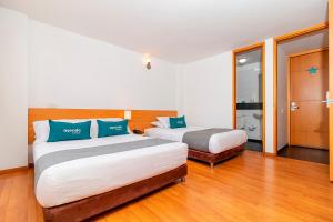 2 łóżka w pokoju z drewnianą podłogą w obiekcie Ayenda Abitare 56 w mieście Bogota