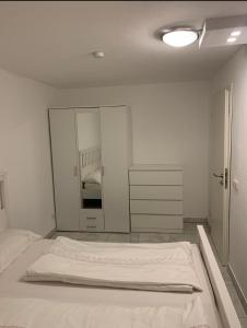 een witte slaapkamer met een bed en een spiegel bij Faridd Ferienwohnung in Krefeld +6 foto's