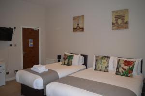 two beds in a room with white walls at Jewel Guest House in Aberdeen