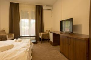 a hotel room with a bed and a flat screen tv at LuxA Apartmani in Novi Pazar