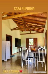 eine Küche mit einem Tisch und Stühlen sowie einem weißen Kühlschrank in der Unterkunft Sitio dos Palmitos - Casa Pupunha in Pedra Azul