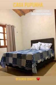 Bett mit einer Decke auf dem Zimmer in der Unterkunft Sitio dos Palmitos - Casa Pupunha in Pedra Azul