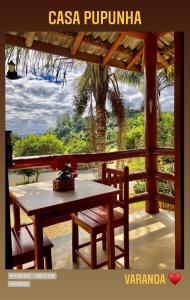 a table and two chairs on a porch with a window at Sitio dos Palmitos - Casa Pupunha in Pedra Azul
