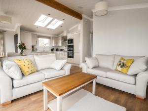 a living room with two white couches and a table at Acorn Lodge in Redruth