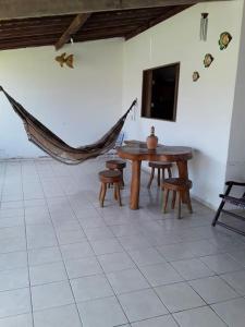 a room with a table and a tv and a hammock at Casa Milagres in São Miguel dos Milagres
