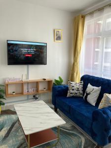 a living room with a blue couch and a tv at Lyshima’s Cozy Studio in Nairobi