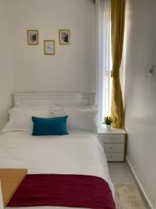 - un lit blanc avec un oreiller bleu et une fenêtre dans l'établissement Lyshima’s Cozy Studio, à Nairobi