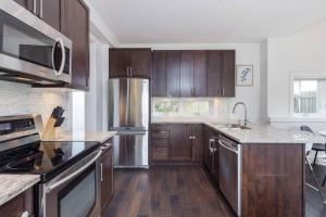 a kitchen with wooden cabinets and stainless steel appliances at West Coast Luxury Living in Vancouver