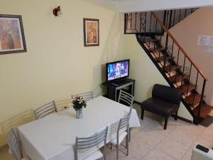 a dining room with a table and a television and a staircase at MAR & ARENA in Puerto Madryn